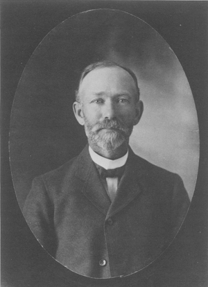 Black and white photograph of a man with a beard wearing a coat.